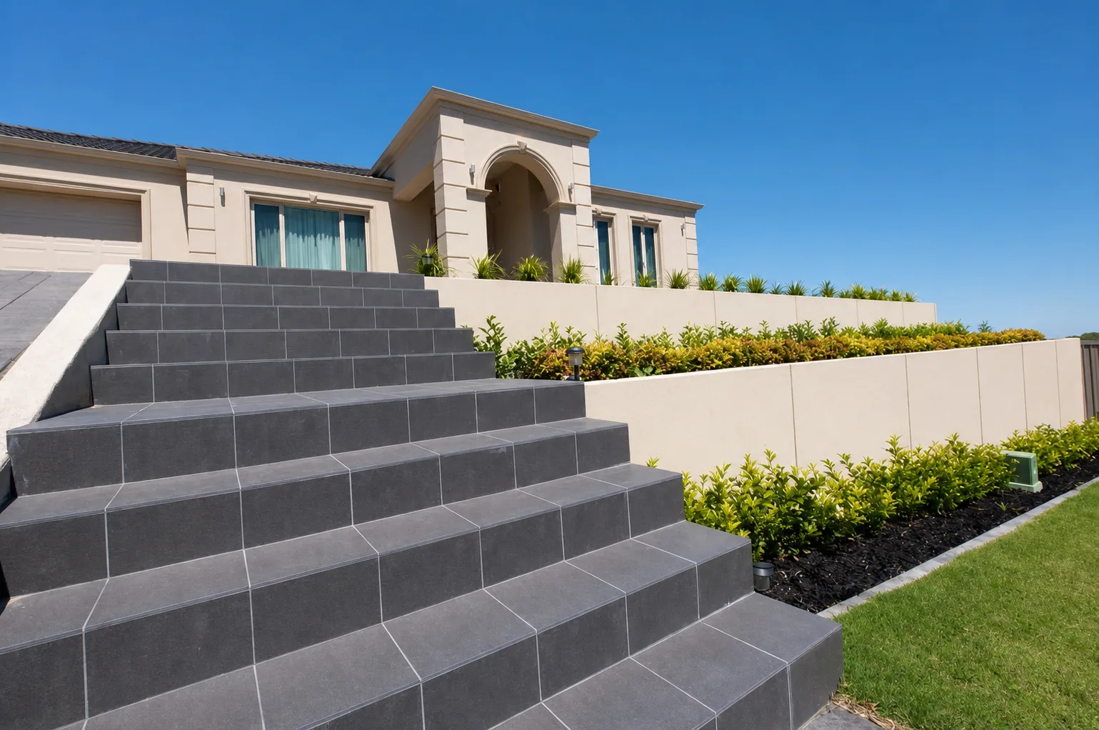 Wide terraced front garden with tiled access steps and retaining walls