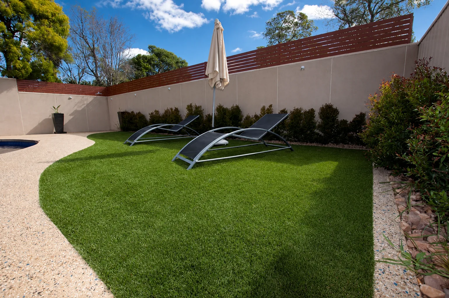Poolside lawn, curved paving and private boundary planting